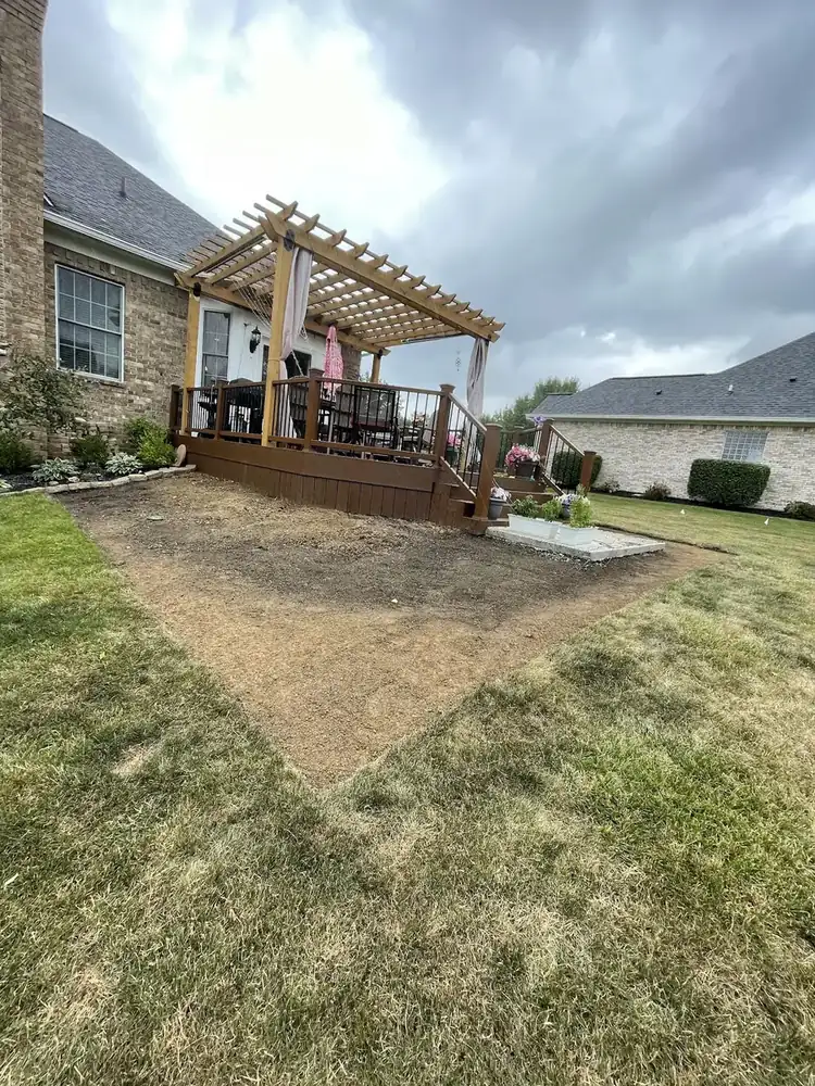 Bare soil area beside a backyard pergola before sod installation